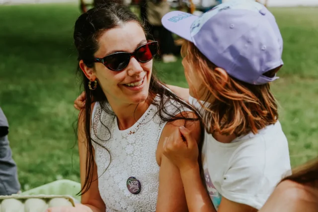 Ein Kind hat die Arme um eine Frau gelegt und sie lächeln sich an