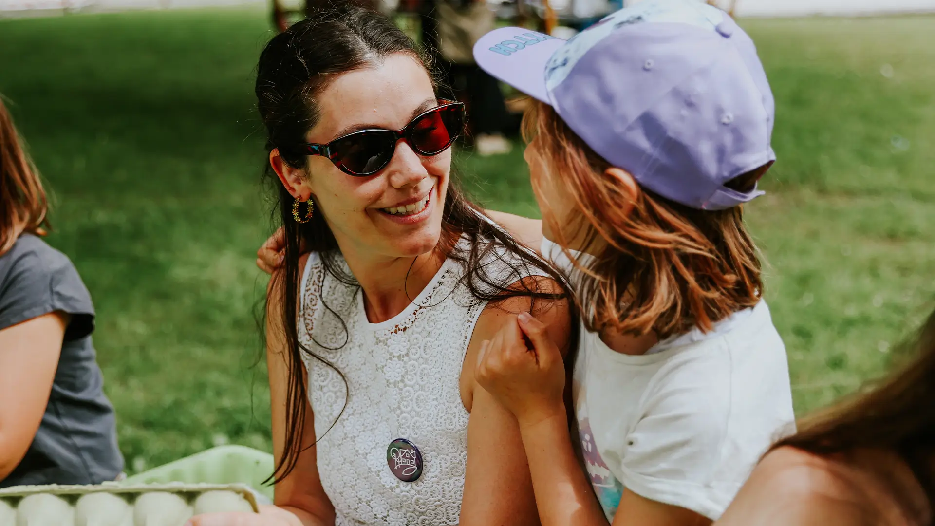 Ein Kind hat die Arme um eine Frau gelegt und sie lächeln sich an