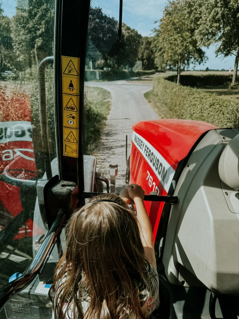 Kind darf Traktor fahren auf einem Pferdestall