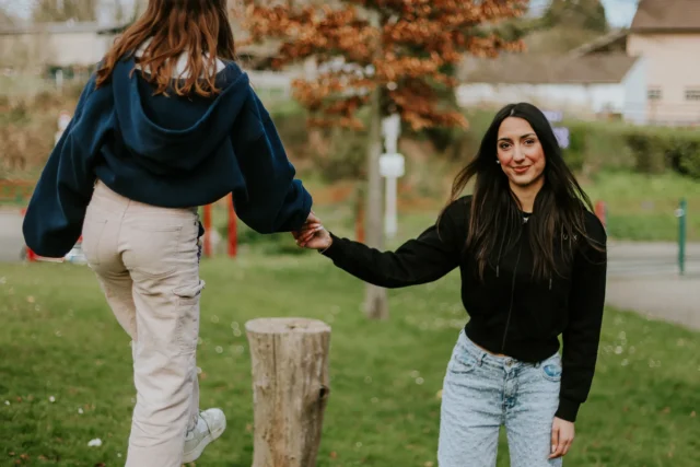 Eine Frau, die ihr freiwilliges soziales Jahr macht, spielt mit einem Mädchen, das balanciert.